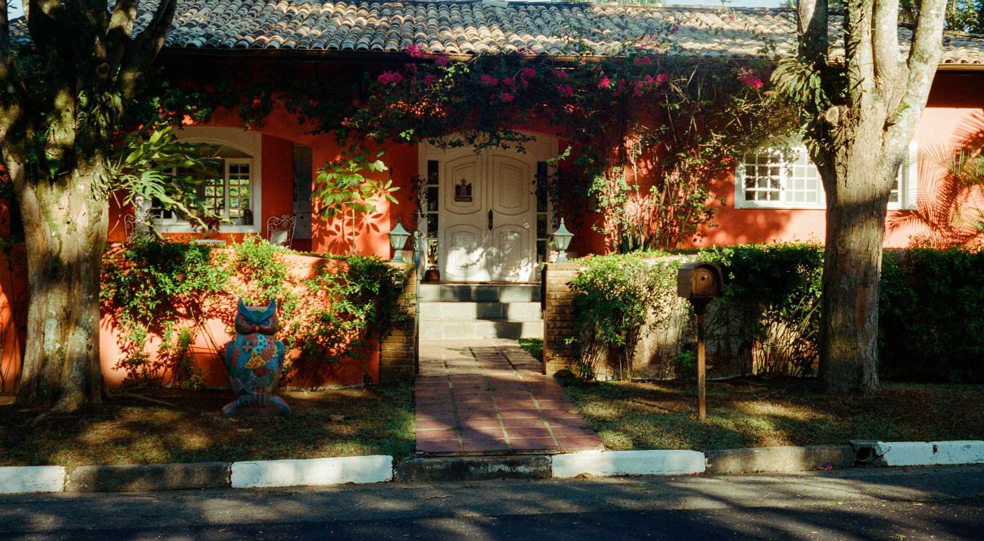 A warm red house with a welcoming front entrance framed by green landscaping