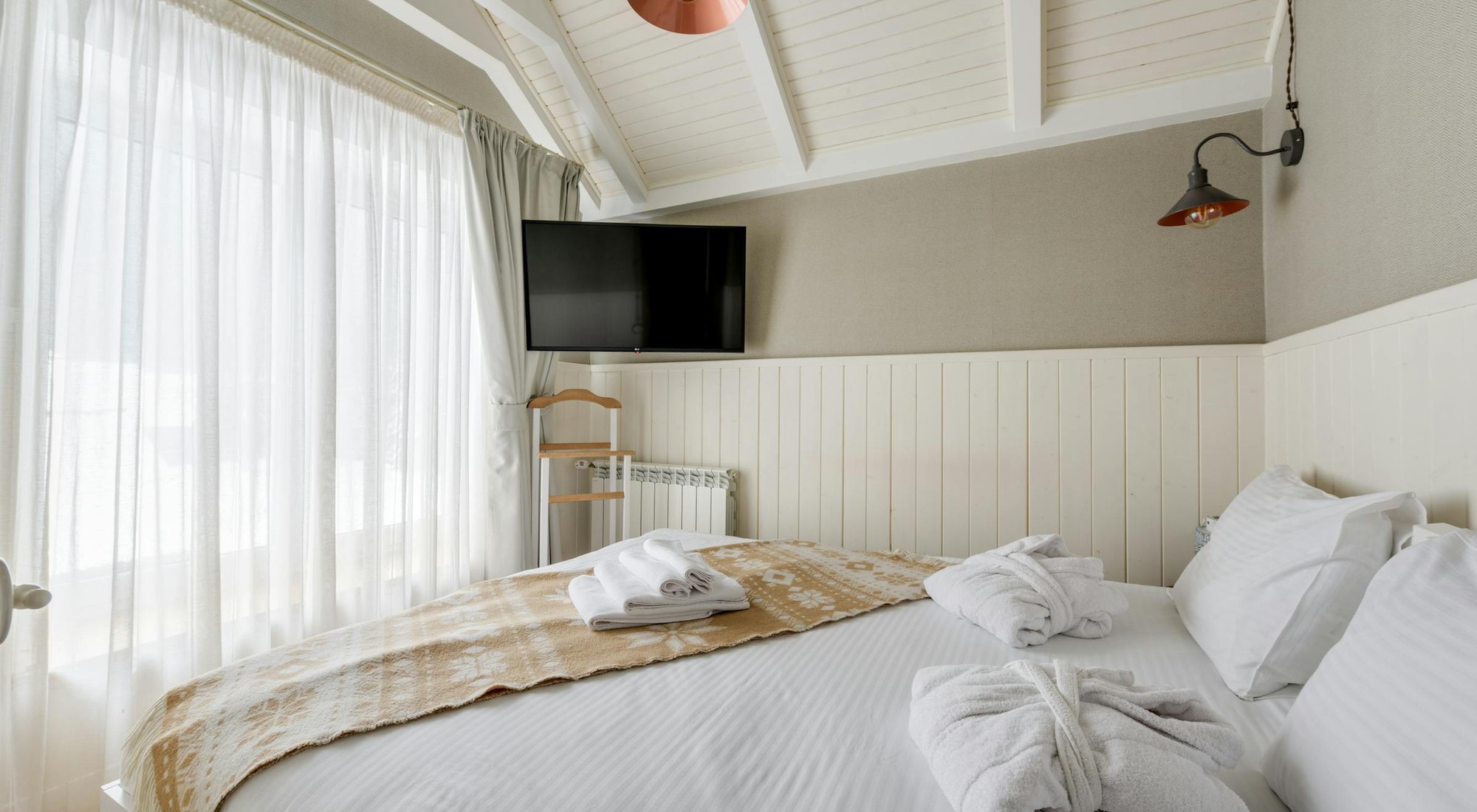 A clean, calm bedroom with a neatly made bed and soft natural light